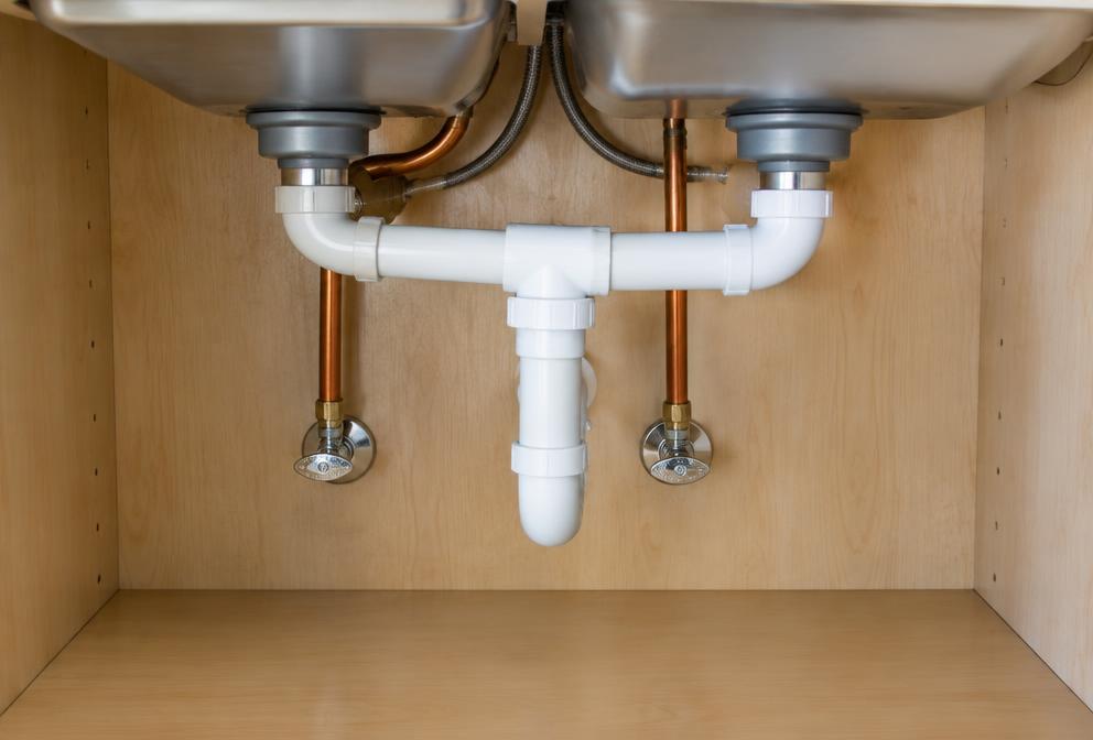 Example photo of new drain and supply lines under a kitchen sink